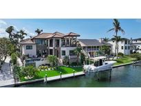 Waterfront home featuring a private dock, boat lift, pool, and manicured landscaping with mature palm trees at 795 Marbury Ln, Longboat Key, FL 34228