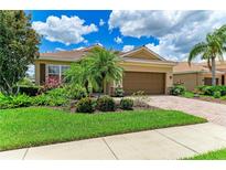 Well-maintained front yard with lush landscaping and a charming home exterior, with a tile roof and brick driveway at 8820 Heritage Sound Dr, Bradenton, FL 34212