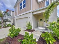 Charming two-story home featuring a well-maintained lawn, two-car garage, and welcoming front porch with rocking chair at 12832 Oak Hill Way, Parrish, FL 34219