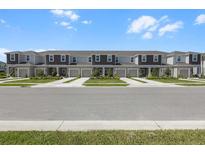 Street view of newly built townhomes with manicured lawns and sidewalks on a sunny day at 16652 Bergamo Pl, Bradenton, FL 34211