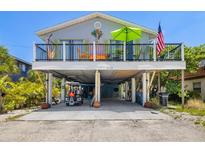 Charming beach house on stilts featuring a vibrant, decorated porch and convenient ground-level parking at 2513 Avenue B # B, Bradenton Beach, FL 34217