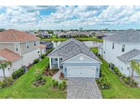 Beautiful single Gathering home featuring a gray tile roof, paver driveway, and a well maintained lawn with landscaped accents at 2565 Star Apple Way, Sarasota, FL 34240