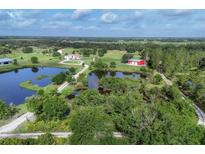 Aerial view of the property with large ponds and red barn at 3045 Logue Rd, Myakka City, FL 34251