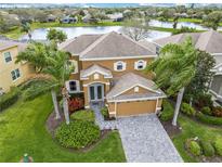 Beautiful home with a tile roof, well-maintained landscaping, and a paver driveway with a lake view in the background at 3671 Summerwind Cir, Bradenton, FL 34209