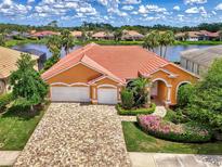 Beautiful orange home with a red tile roof, lush landscaping, and a paver driveway at 4957 Sabal Lake Cir, Sarasota, FL 34238