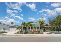 Charming home exterior with mature landscaping, inviting Adirondack chairs, and coastal charm at 509 Pine Ave # A, Anna Maria, FL 34216