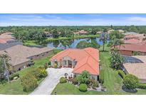 Beautiful lake view home with a red tile roof and mature landscaping in a desirable neighborhood at 5523 Secluded Oaks Way, Sarasota, FL 34233