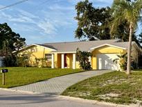 Charming yellow single-story home featuring a well-maintained lawn, palm trees, and a paved driveway at 5615 Waneta Pl, Sarasota, FL 34231