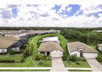 An aerial view of a charming home with a pond view, lush lawn, and brick paved driveway at 6507 Clairborne Ln, Bradenton, FL 34211