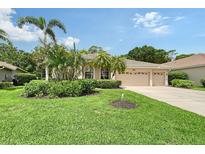 Charming home featuring a well-manicured lawn, lush landscaping, and a spacious three-car garage at 7464 Ridge Rd, Sarasota, FL 34238