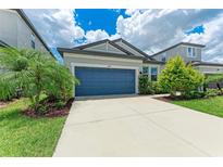 Charming single Gathering home showcasing a blue garage door and well-manicured landscaping at 8721 Firefly Pl, Parrish, FL 34219