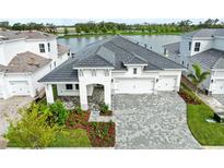 Stunning home exterior featuring a three-car garage, elegant landscaping, and a serene lake view at 10309 Longmeadow Ave, Parrish, FL 34219