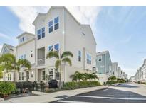 Charming two-story townhome features a white exterior, balcony, and a fenced-in patio with lush landscaping at 2500 Boone Ct, Sarasota, FL 34237