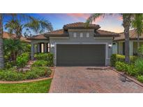 Charming home featuring a brick driveway, a two-car garage, manicured landscaping, and a tile roof at 2525 Daisy Dr, North Port, FL 34289