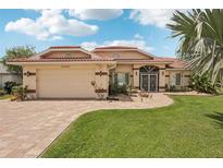 Charming single-story home features a red tile roof, lush landscaping, and a brick paver walkway and driveway at 25433 Colon Dr, Punta Gorda, FL 33983