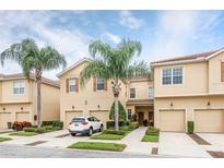 Two-story townhome featuring a beige exterior, attached garage, and palm trees on a sunny day at 3698 Parkridge Cir # 26-104, Sarasota, FL 34243