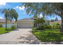 Charming single-story home featuring a manicured lawn, mature trees, and a two-car garage, enhancing curb appeal at 5419 Lakehurst Ct, Palmetto, FL 34221