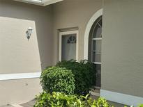 Inviting front entrance with neutral stucco, front door, arched window, and manicured landscaping at 6908 Stoneywalk Ct, Bradenton, FL 34203