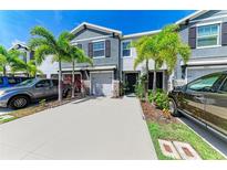 Charming townhome with a well-manicured lawn, lush landscaping, and a driveway with two cars at 8676 Ice Wine St, Sarasota, FL 34238