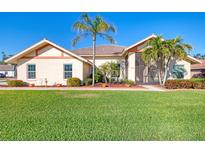 Charming single-story home featuring a well-manicured lawn, mature palm trees, and a welcoming facade under a clear blue sky at 1144 Hoover St, Nokomis, FL 34275