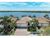 Stunning aerial view of lakefront property with well-maintained landscaping and a beautiful tile roof at 138 Toscavilla Blvd, Nokomis, FL 34275