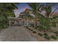 Charming two-story home with tropical landscaping, brick driveway, and covered parking at 160 Coolidge Dr, Sarasota, FL 34236