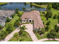 An aerial view of an estate home with a tile roof, circular drive, and a private lake view at 16531 Kendleshire Ter, Lakewood Ranch, FL 34202