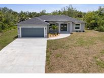 Charming one-story home featuring a large driveway, a two-car garage, and a well-maintained yard at 19185 Sherbrooke Ave, Port Charlotte, FL 33954