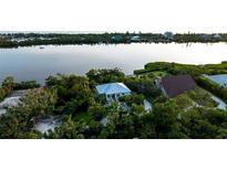 Beautiful waterfront home featuring a metal roof and mature tropical landscaping, nestled amidst lush greenery at 2048 Larson St, Englewood, FL 34223