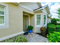 Inviting home entrance with olive front door, textured walls, manicured landscaping, and tiled walkway at 3681 Divot Ln, Sarasota, FL 34232