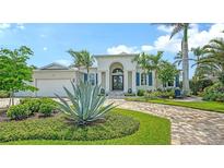 Elegant home featuring manicured landscaping, a brick driveway, and stately architectural details at 413 Partridge Cir, Sarasota, FL 34236