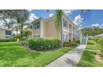 Inviting exterior view of a two-story condo with lush landscaping and charming turquoise shutters at 4211 Caddie E Dr # 202, Bradenton, FL 34203