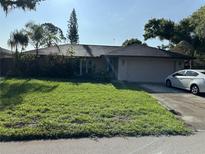 Charming single-story home with lush green lawn and mature trees under a bright sky at 4343 Arrow Ave, Sarasota, FL 34232