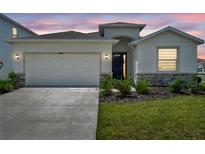 Charming single-story home showcasing manicured landscaping, a two-car garage, and a welcoming entrance at 4405 Weathered Moss Gln, Palmetto, FL 34221