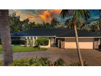 Charming single-story home featuring a black roof, stone accents, paved driveway, and lush landscaping at 483 Partridge Cir, Sarasota, FL 34236