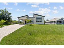 Striking modern home with lush lawn, covered parking, and charming front yard landscaping at 5339 Gulfport Ter, Port Charlotte, FL 33981