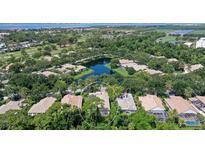 An aerial view of a home situated on a verdant lot, surrounded by a pond, lush trees, and a golf course in the distance at 5839 Los Verdes Ct, Bradenton, FL 34210