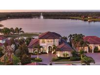 Stunning waterfront home with a tile roof, lush landscaping, and a brick driveway at 7665 Haddington Cv, Bradenton, FL 34202