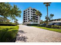 Beautiful condominium complex with well-manicured lawns and a brick-paved driveway leading up to the building at 8735 Midnight Pass Rd # 602B, Sarasota, FL 34242