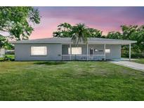 Charming single-story home with a spacious front yard and a welcoming covered porch under a colorful sunset at 2622 11Th W Ave, Bradenton, FL 34205