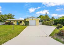 Charming one-story home featuring a well-manicured lawn, a two-car garage, and a bright yellow exterior at 409 Archibald Ave, Sarasota, FL 34243