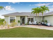 Charming single-story home with a well-manicured lawn, landscaping, and quaint front patio seating at 6178 Coliseum Blvd, Port Charlotte, FL 33981