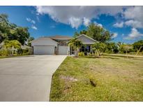 Charming single-story home with a well-manicured lawn, a two-car garage, and tropical landscaping at 640 Encarnacion St, Punta Gorda, FL 33983