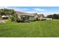 Single-story home with lush landscaping, light tan exterior, and well-manicured lawn at 1112 Golfview Woods Dr # 1112, Sun City Center, FL 33573