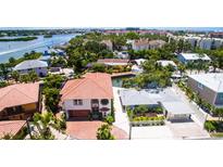 Charming waterfront home with a red tile roof, mature trees, and lush landscaping at 1240 Solitude Ln, Sarasota, FL 34242