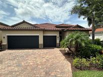 Charming home featuring a two-car garage, red tile roof, and meticulously landscaped front yard at 13422 Saw Palm Creek Trl, Lakewood Ranch, FL 34211