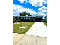 Charming single-story home with a well-manicured lawn and a long driveway leading to a covered carport at 1604 Chevy Chase Dr, Sun City Center, FL 33573