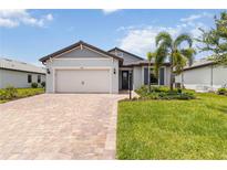 Charming single-Gathering home with a brick driveway, manicured lawn, and tropical landscaping at 7758 Summerland Cv, Bradenton, FL 34202