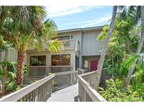 Charming two-story home featuring a balcony, a red door, and lush tropical landscaping at 1347 Landings Dr # 6, Sarasota, FL 34231