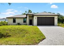 Charming one-story home featuring a two-car garage, neutral color palette, and well-manicured lawn with paver driveway at 1532 Maricopa Rd, North Port, FL 34287
